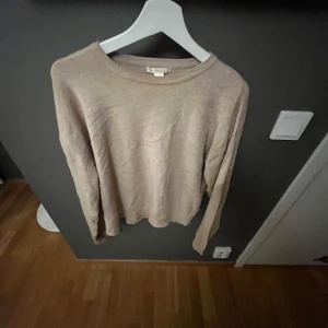 Beige tröja - Säljer en stilren beige tröja med rund halsringning. Tröjan har långa ärmar och är perfekt för en avslappnad look. Passar bra till både jeans och kjol.