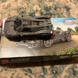 LEGO Speed Champions Pagani Utopia - Byggsats från LEGO Speed Champions som föreställer en Pagani Utopia. Setet innehåller en detaljerad modell av bilen i grått och en minifigur med hjälm och verktyg. Perfekt för bilentusiaster och LEGO-samlare.