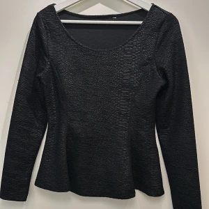 Topp från H&M - Snygg svart topp från H&M med långärmad design och texturerat mönster. Perfekt för en stilren look.
