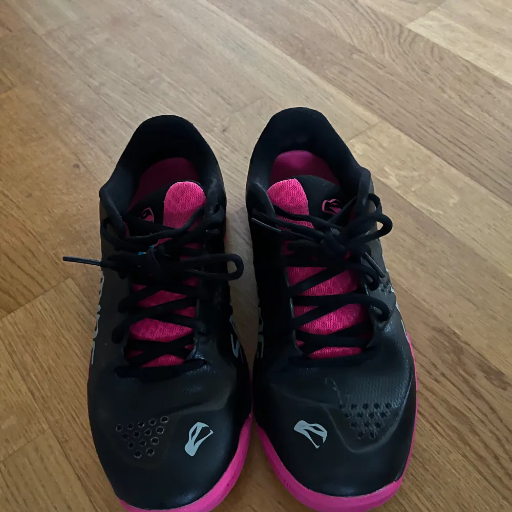 Säljer ett par snygga Salming sneakers i svart och rosa. Skorna har en sportig design med snörning och Salming-loggan på sidan. De är perfekta för träning eller vardagsbruk. Skorna är i bra skick och redo för nya äventyr! Köpt för 899 säljer 699. Skor.