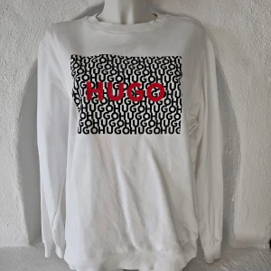 Sweatshirt/ crewneck från Hugo  - Vit sweatshirt från Hugo med svart och rött tryck. Använd och tvättad 1 gång.