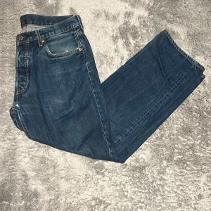 Levi’s 501 jeans; Relaxed fit - Säljer mina gamla levis 501 då jag inte riktigt diggar passformen längre, jeansen är i använd skick. Det finns en slitning som går att laga vid slutet av gylfen, se sista bilden. Tycker dessa jeans har en riktigt skön färg och att de har liv kvar✌🏻