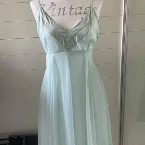 Ljusblå långklänning från Vila - Säljer en superfin ljusblå långklänning från Vila. Den har en elegant v-ringning och smala axelband som ger en romantisk känsla. Klänningen är i ett lätt och flödande material. Den har en diskret dragkedja på sidan för enkel påklädning.