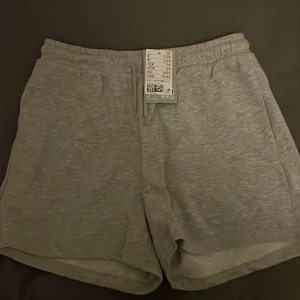 Grå mjukisshorts från H&M - Säljer ett par grå mjukisshorts från H&M i storlek S. De är superbekväma och perfekta för en avslappnad dag hemma eller en snabb tur till affären. Shortsen har en elastisk midja och är gjorda i mjukt material. Perfekta för sommaren eller våren!