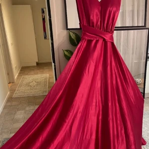 Rosa långklänning i satin - Fantastisk rosa  långklänning i satin med en elegant v-ringning och inbyggd bh. Klänningen har en vacker omlott-detalj i midjan som ger en smickrande siluett. Perfekt för festliga tillfällen som nyår eller bal. *skräddarsydd* 