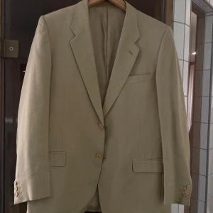 Beige kavaj från Marzotto - Säljer en stilren beige kavaj från Marzotto, tillverkad i Italien. Kavajen har en klassisk design med två knappar framtill och fickor med lock.