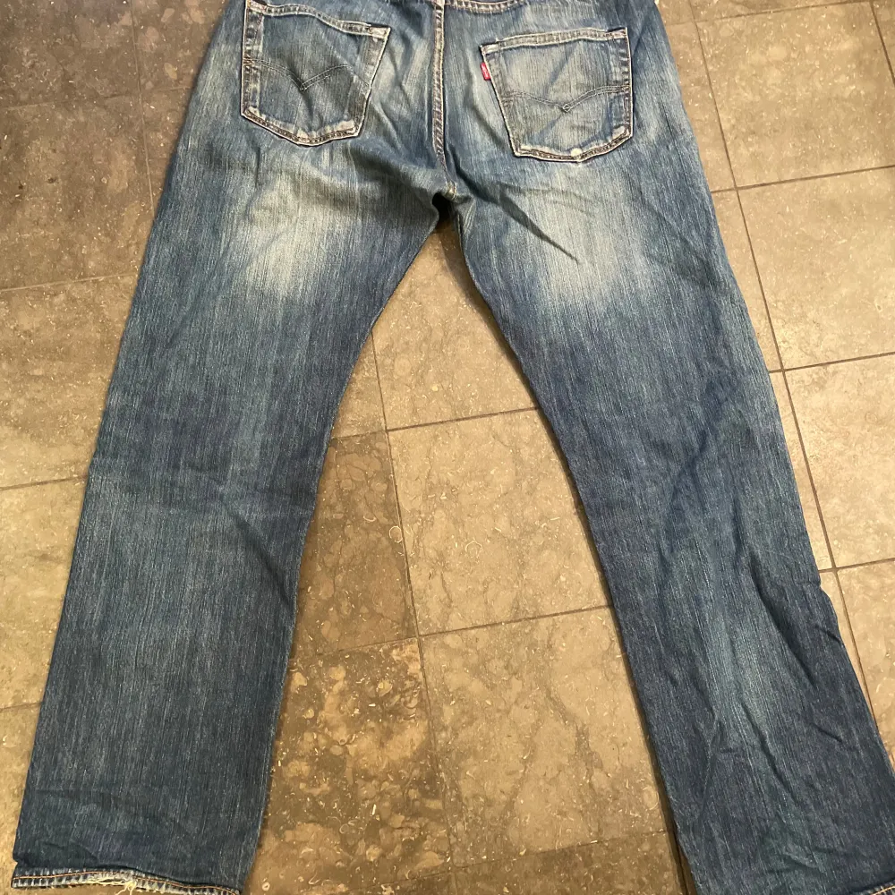 Säljer ett par klassiska Levis 501 jeans i blå denim. De har en vintage look med slitningar och fransiga kanter med nice wash.. Jeans & Byxor.