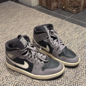 Nike Air Jordans i grått och svart - Snygga Nike Air Jordans i grått och svart med klassisk snörning och vit sula. Perfekta för dig som vill ha en stilren och sportig look. De har den ikoniska Air Jordan-loggan på sidan. Det finns små slitningar på skorna, men inget som syns på håll, skriv för närbild. 