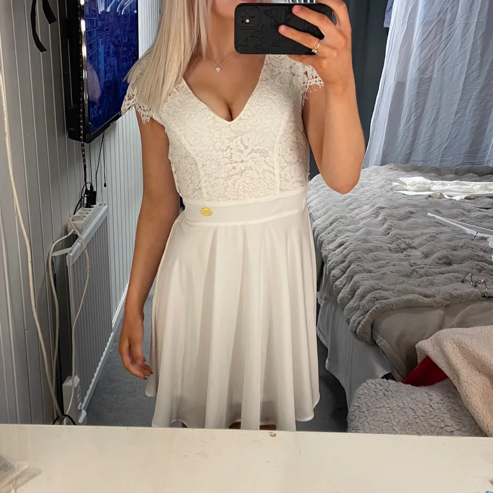 Säljer en vacker vit klänning från Chiara Forthi med spetsdetaljer och v-ringning. Klänningen har korta ärmar och en öppen rygg med elastisk midja för en bekväm passform. Perfekt för student eller sommarens festligheter!🤍. Mekot.