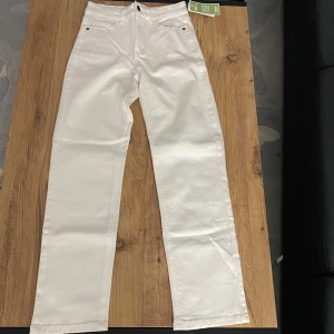 Vita jeansbyxor - Snygga vita jeansbyxor med hög midja och raka ben. Perfekta för en stilren look. Byxorna har klassisk femficksdesign och knappgylf. Har aldrig använt, den är helt ny och där kan ni se lappen.