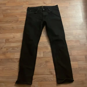 Svarta jeansbyxor från lee - Snygga svarta jeansbyxor med en klassisk design. De har en rak passform och är perfekta för en stilren look.