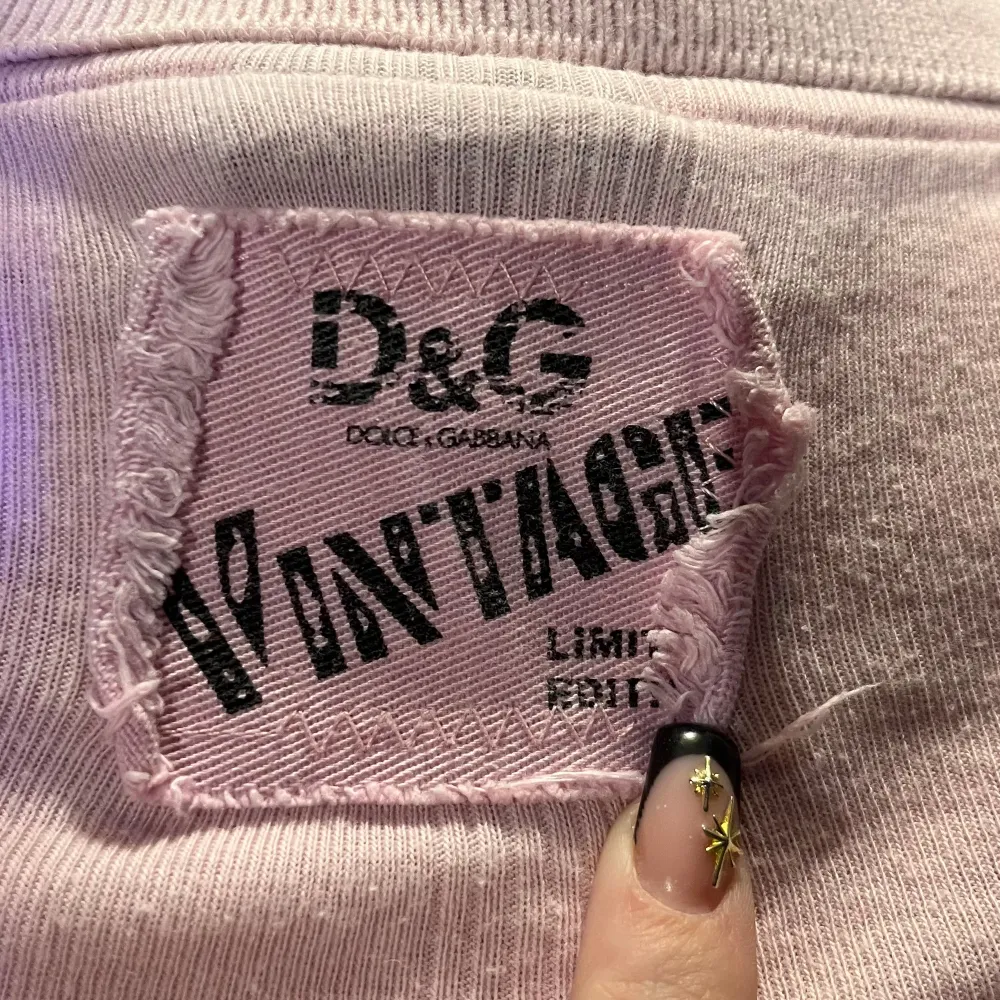 Säljer en rosa topp från Dolce & Gabbana med korta ärmar och knappar framtill. Toppen har en vintage-look med en tydlig logga på baksidan. Perfekt för dig som gillar en stilren och klassisk design.. Yläosat.