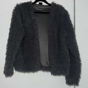 Grå teddyjacka från Gina Tricot - Säljer en mysig grå teddyjacka från Gina Tricot. Jackan har en fluffig yta och är perfekt för kyligare dagar. Den är långärmad och har en stilren design utan knappar eller dragkedja.perfekt till fest osv😍