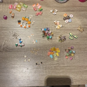 Färgglada örhängen i olika former - Säljer ett set med olika örhängen i roliga och färgglada former som avokado, pumpor, enhörningar och drycker. Perfekt för att lägga till en lekfull touch till din outfit. Örhängena har olika färger och mönster. Och det finns påsar till