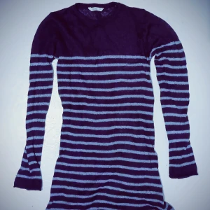 Randig stickad lång tröja - Stickad lång tröja med mörklila och ljuslila ränder. Den har långa ärmar och en bekväm passform som passar perfekt för kyligare dagar.