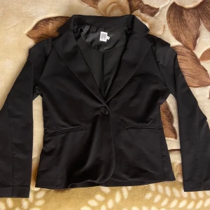 Klassisk svart blazer från Saint Tropez - stl. M  - Klassisk svart blazer som passar alla tillfällen, fin att ha till nyår! Från märket Saint Tropez, äkta. Har en kavajkrage, en knappknäppning, 2 stora fickor framtill (insydda, ej funktionella) och en normal passform. Långa ärmar. Skick: Mycket fint skick. Nypris: 699 kr 