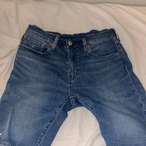 Levi's Premium Jeans - Säljer ett par klassiska Levi's Premium jeans shorts, modell 502. De är blåa med vit färg med en normal passform och har en knappgylf. Perfekta för en avslappnad stil.