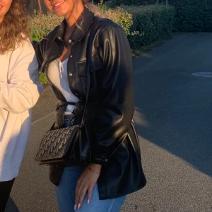 Svart skinnjacka - Snygg svart skinnjacka, oversized med skärp Perfekt för höst och vår med långa ärmar och knappar framtill. 