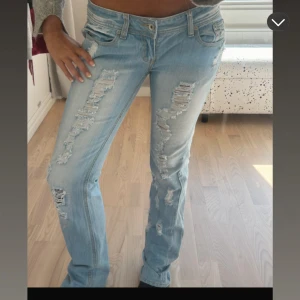 Ljusa slitna jeans - Säljer ett par ljusa jeans med slitningar. De har en tight passform och låg midja, perfekt för en avslappnad stil. Jeansen är i bra skick och passar till både vardag och fest.