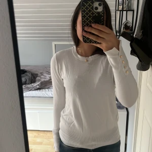 Vit tröja med knappar - Säljer en stilren vit tröja med långa ärmar och snygga guldfärgade knappar vid ärmsluten. Perfekt för både vardag och festliga tillfällen. Tröjan är i bra skick och passar utmärkt till höst- och vintergarderoben. Supermjuk och bekväm! ❤️Obs. ingen krage som visas på tredje bilden då den här modellen är slutsåld på ZARAs hemsida