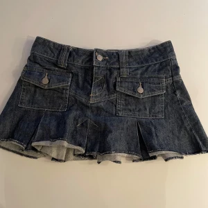 Vintage Mini Jeanskjol med fickor - Säljer en söt jeanskjol i kort modell med snygga fickdetaljer fram. Kjolen har en klassisk blå denimfärg och är perfekt för sommarens alla äventyr. Den har en bekväm passform och är lätt att matcha med olika toppar. Perfekt för en avslappnad och trendig look! 💙