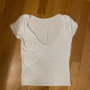 Vit kortärmad topp - Säljer en enkel och stilren vit topp i bomull. Den är kortärmad och har en djup rygg, vilket ger en snygg och luftig känsla. Toppen är i bra skick och passar till det mesta!🤍