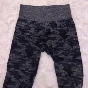 Grå camo leggings från Gymshark - Säljer ett par grå camo leggings från Gymshark. De är perfekta för träning med sin tighta passform och höga midja. Materialet är mjukt och stretchigt, vilket gör dem superbekväma att ha på sig. Perfekta för gymmet eller en aktiv vardag! Köpa av en tjej men dem ligger bara i garderoben 🩷