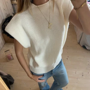 Vit stickad ärmlös topp - Säljer en superfin vit stickad topp som är ärmlös. Den har en hög krage och en loose passform som gör den både bekväm och stilren. Som ny❤️❤️