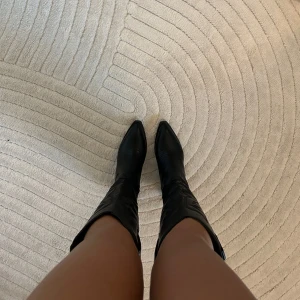 Svarta cowboy boots med klack - Snygga svarta cowboy boots i skinnimitation med spetsig tå och broderade detaljer. De har en klack på 7 cm som ger lite extra höjd. Perfekta för höst och vinter, och funkar lika bra till vardags som till fest. Skorna är helt nya och aldrig använda då jag har ett par till liknande. Storlek 40 men skulle säga att de är mer som 39.