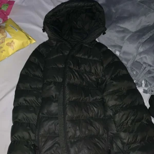 Svart dunjacka från Peak Performance - Säljer en mörkgrön dunjacka från Peak Performance i mycket bra skick. Jackan är perfekt för vintern med sin varma och puffiga design. Den har en dragkedja framtill och en praktisk huva för extra skydd mot kylan. Passar både till vardags och utomhusaktiviteter. Använd endast 7 gånger max. Helt ny skick inga märken eller defekter.