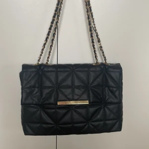 Väska - En svart väska i fint skick, dock har en knapp ramlat av (se bild 3). Annars bra skick använd fåtal ggr💕