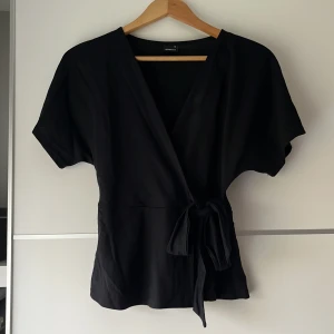 Omlotttopp - Svart omlotttopp från Gina Tricot i storlek 34