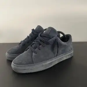 Säljer ett par snygga mörkblå sneakers i mocka. De har en stilren design med snörning och en bekväm sula. Perfekta för både vardag och fest! Skorna är i bra skick och redo för nya äventyr. Ny pris 1999