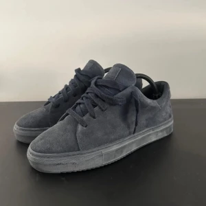 Mörkblå mocka sneakers J.lindeberg - Säljer ett par snygga mörkblå sneakers i mocka. De har en stilren design med snörning och en bekväm sula. Perfekta för både vardag och fest! Skorna är i bra skick och redo för nya äventyr. Ny pris 1999