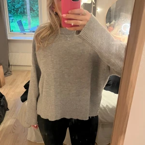 Grå stickad tröja  - Stickad tröja som bara använts en gång och är i bra skick, har en slit på sidorna