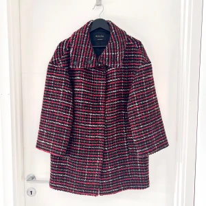 Rutig kappa från Massimo Dutti - Säljer en snygg rutig kappa i ullblandning från Massimo Dutti. Den har en klassisk design med en mix av rött, svart och vitt i ett stilrent mönster. Perfekt för höst som övergångskappa, och ger en elegant touch till vilken outfit som helst. Kappan är tillverkad i Portugal och har en bekväm passform.