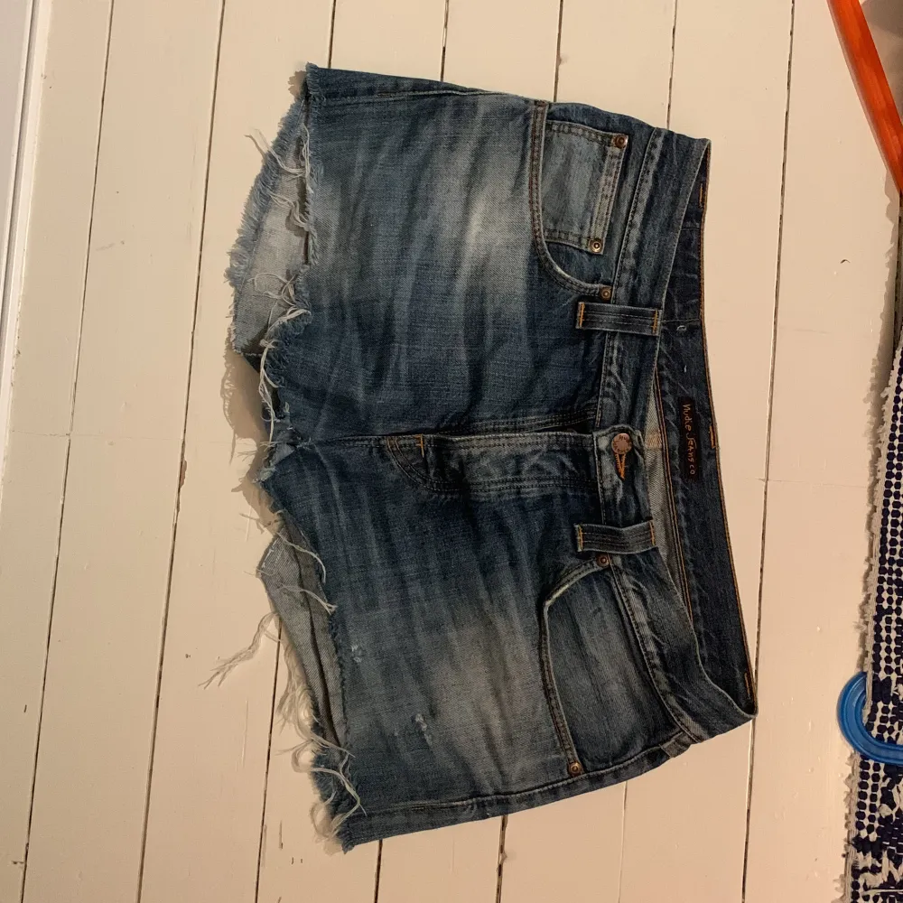 Säljer ett par snygga blå jeansshorts från Nudie Jeans. De har en cool, fransig kant och klassisk femficksdesign. Perfekta för sommaren och ger en avslappnad look. Passar bra till både t-shirt och linne!. Shorts.