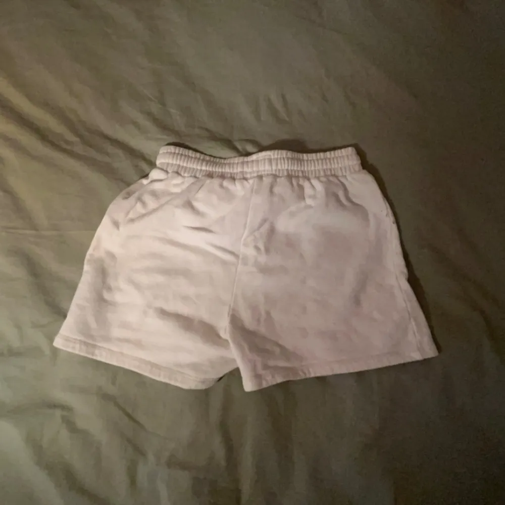 Säljer ett par vita shorts i bomull. De har en elastisk midja för en bekväm passform. Perfekta för en avslappnad dag hemma eller en promenad i parken. Observera att det finns en liten fläck på framsidan.. Shorts.