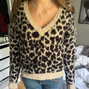 Leopardmönstrad stickad tröja - Säljer en supermysig leopardmönstrad stickad tröja med v-ringning. Den är perfekt för höst och vinter och har långa ärmar. Tröjan är i en beige och svart. Den är i relativt bra skicka, lite nopprig bara🩷
