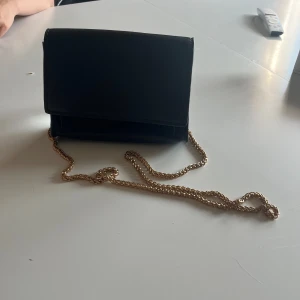 Svart handväska med guldband - En svart väska med guldband andvänd fåtal gånger 