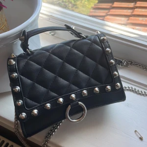 Svart väska - Säljer denna skitcoola svarta nitväskan från Zara💓 Jättefint skick, inga skavanker eller defekter! Nypris 400kr! Har både kort och långt band och rymmer telefon, plånbok, smink ja vad man nu behöver!  Säljer även kjolen o tröjan så kika gärna på dem☺️