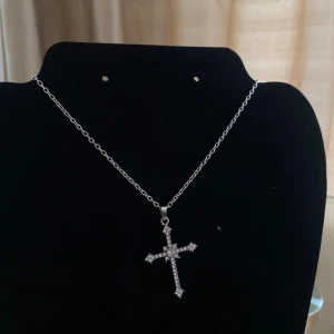 Silverfärgat halsband med korshänge - Snyggt och stilrent silverfärgat halsband med ett glittrande korshänge. Perfekt för att ge en elegant touch till vilken outfit som helst. 💓