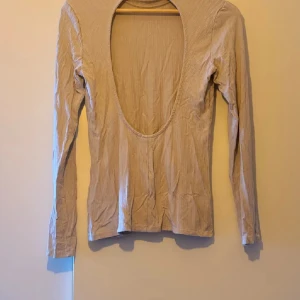 Beige långärmad topp - Säljer en stilren beige långärmad topp med djup urringning. Perfekt för både vardag och fest. Materialet är mjukt och bekvämt, vilket gör den idealisk för höst och vår.