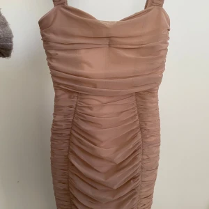 Beige/Rosa tight långklänning - Storlek S. Aldrig använd. Köpt för 699kr. Tight långklänning som slutar vid vaderna på mig som är 163
