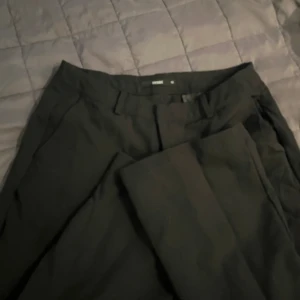 Svarta kostymbyxor från Bik Bok - Säljer ett par stilrena svarta kostymbyxor från Bik Bok. De är perfekta för både jobb och festliga tillfällen. Byxorna har en klassisk design med knappar och dragkedja framtill. De är i storlek 40 men är små i passformen så skulle säga att det är 38.