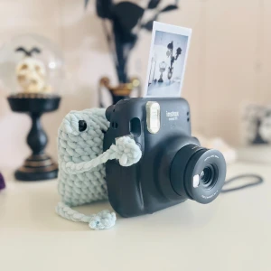 Instax Mini 11 med stickad kameraväska - Säljer en supersöt groda med ben i en ljusgrön färg. Perfect som decorarion i hemmet eller som en liten kompis. Kameran är inte till salu uren det är grodansom man köper***.