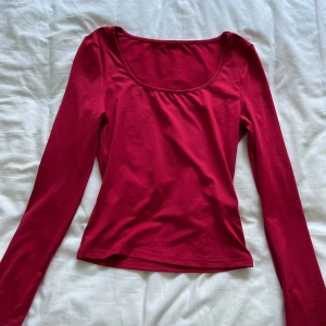 Röd långärmad topp - Säljer en snygg röd långärmad topp. Den är gjord av ett mjukt och bekvämt material, perfekt för både vardag och fest. Toppen har en rund halsringning och en tight passform som framhäver figuren. Perfekt för höst och vinter!
