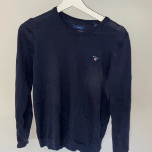 Mörkblå tröja från GANT - Säljer en snygg och stilren mörkblå tröja från GANT. Den har en klassisk design med rund hals och långa ärmar. Perfekt för både vardag och lite finare tillfällen. Tröjan är i bra skick och har GANT-loggan broderad på bröstet.