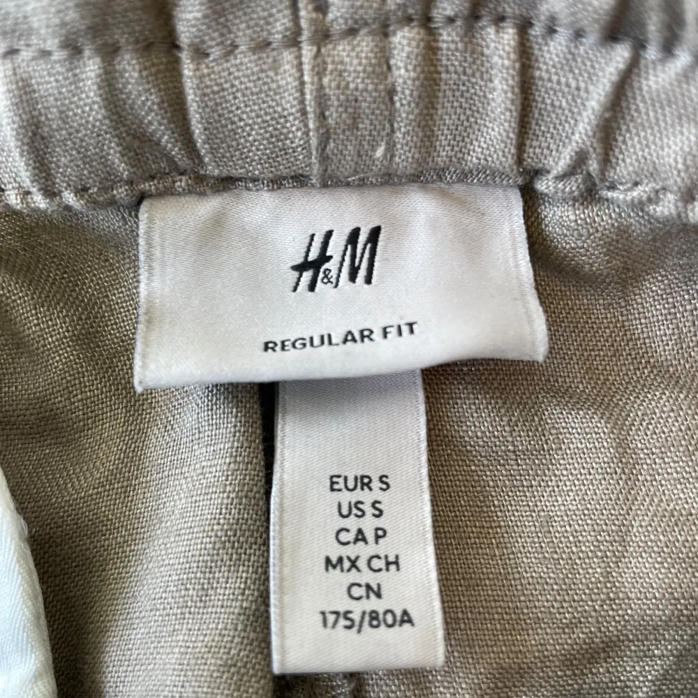 Säljer ett par riktigt bekväma beige linnebyxor från H&M i storlek S. Byxorna har en elastisk midja med snörning för extra komfort. Perfekta för en avslappnad stil under varma dagar. De är i regular fit och passar bra till både vardag och sommaraktiviteter.. Jeans & Byxor.