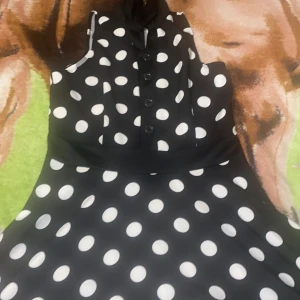 Svart prickig klänning från iHot - Säljer en superfin svart klänning med vita prickar från iHot. Den har knappar framtill och en dragkedja i ryggen. Perfekt för en festlig kväll eller en somrig dag! 🌟